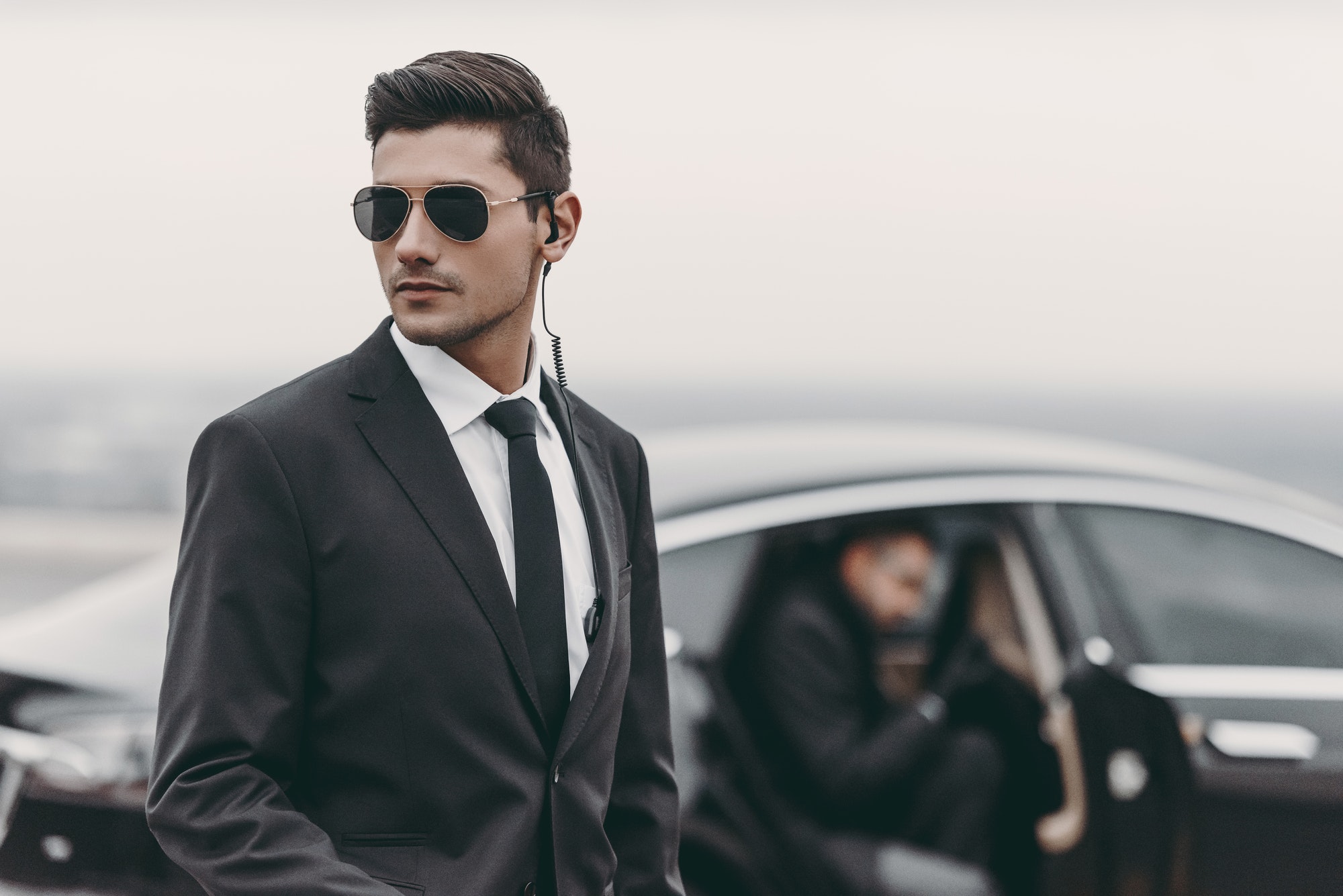 bodyguard reviewing territory while businessman going out from car