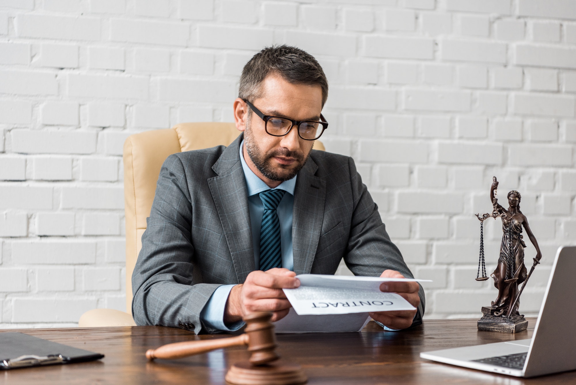 serious male lawyer in eyeglasses working with contract in office
